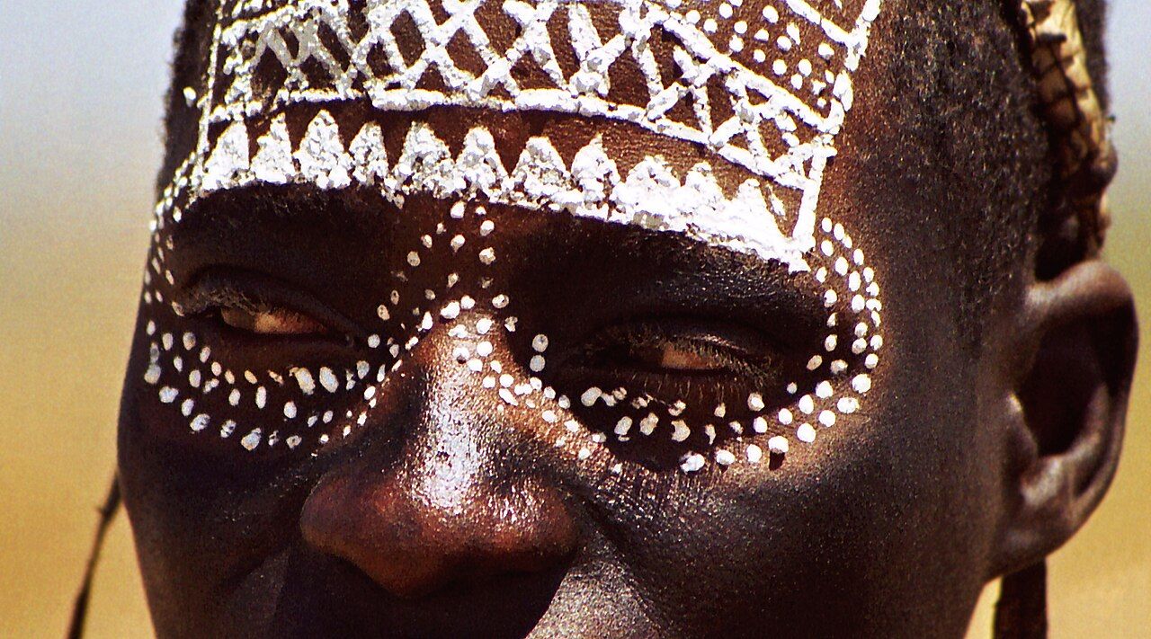 A young Maasai man with white face paint marking his passage into a new social status