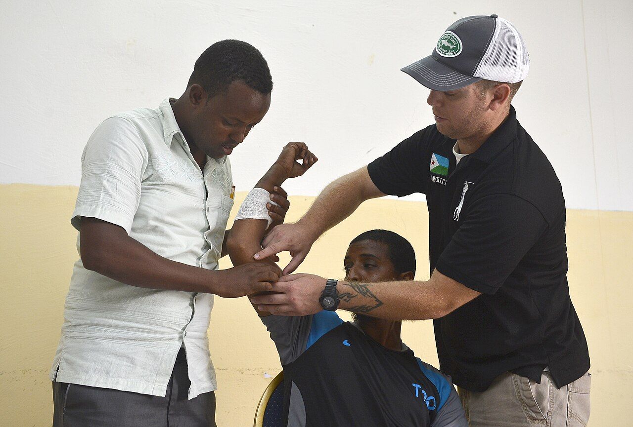 A community health worker measuring a patient’s blood pressure at a table in a neighbourhood clinic setting