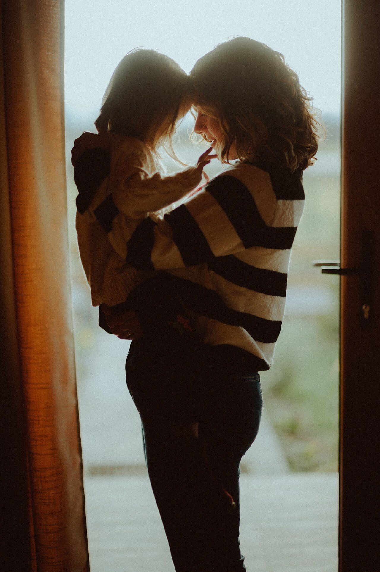A parent holding a young child close in a doorway