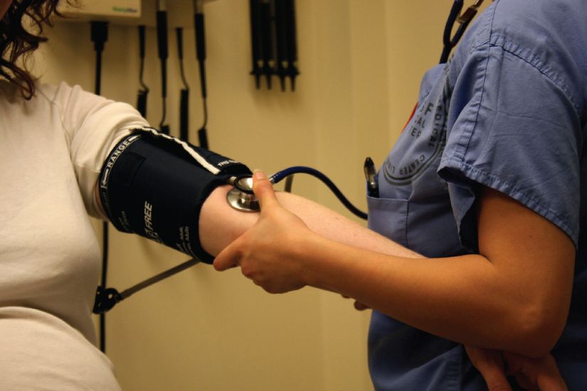 Blood pressure measurement reference figure showing sphygmomanometer cuff technique