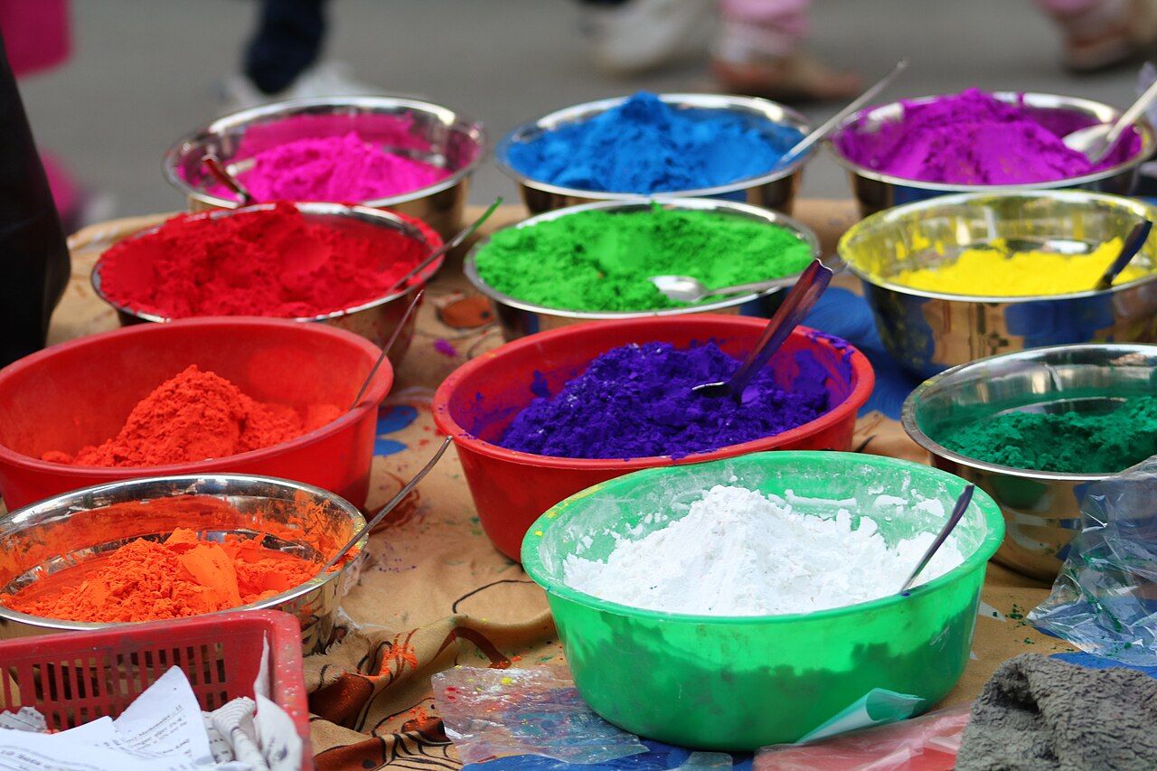 A crowd celebrating the Holi festival, covered in bright colored powder