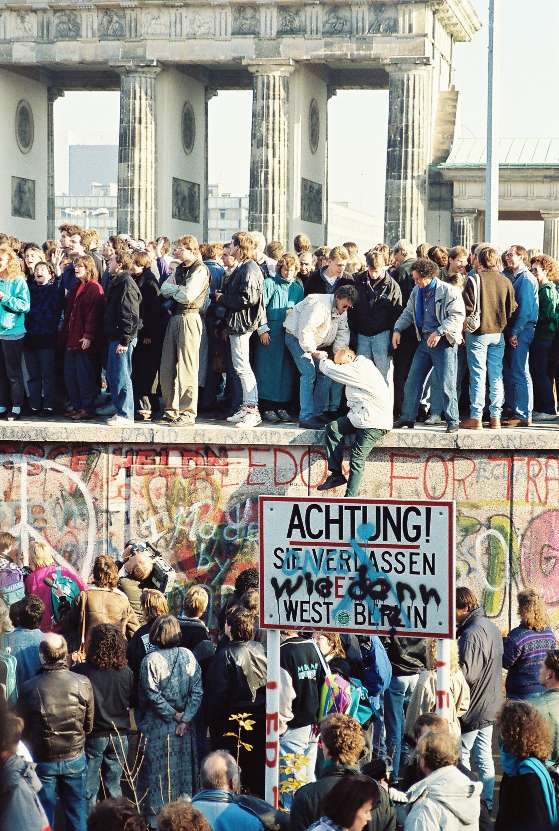 Berliners on the Wall at the Brandenburg Gate in November 1989 — a border that had killed people for twenty-eight years opened in a single evening of confusion.